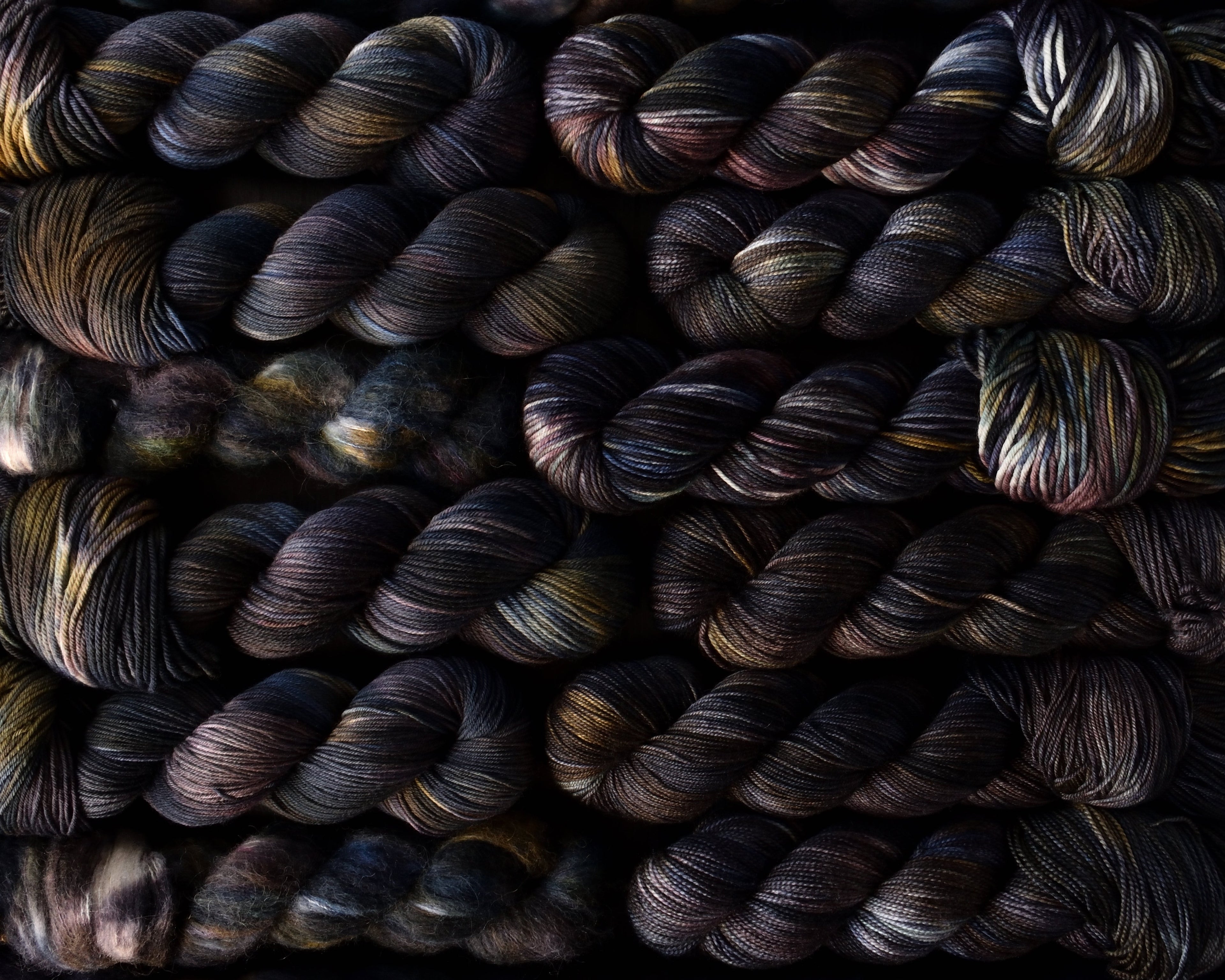 Close-up of darkly colored yarn skeins with subtle variations.